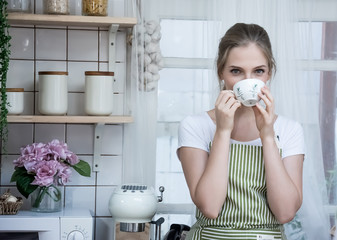 A woman sitting and drinking coffee in the kitchen