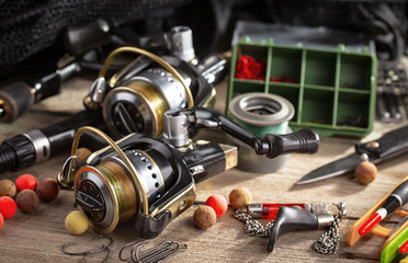 Fishing rods and spinnings in the composition with accessories for fishing on the old background on...