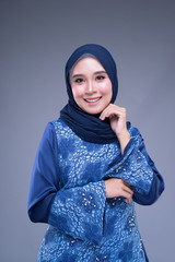 Half length portrait of a beautiful Muslim female model in various poses wearing modern kurung, urban lifestyle apparel for Muslim women isolated on grey background. Beauty and hijab fashion concept