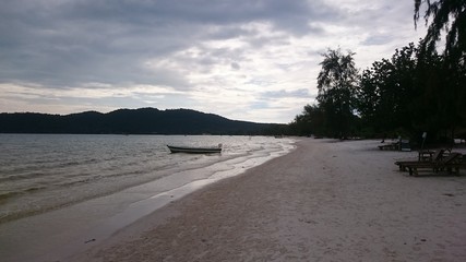 Seaview with cloudy sky and silhouette of a fisherman boat, hills and tree