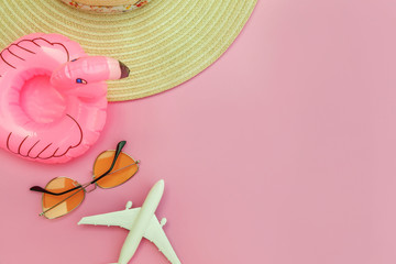 Summer beach composition. Minimal simple flat lay with plane sunglasses hat and Inflatable flamingo isolated on pastel pink background. Vacation travel adventure trip concept. Top view copy space.