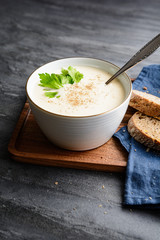 Delicious creamy celery soup topped with black pepper and fresh leaves, served with crusty bread