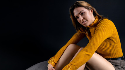 charming young girl with a sensual look on a dark background, copy space