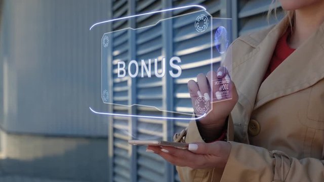 Unrecognizable businesswoman interacts HUD hologram with text Bonus. Woman in the coat uses the technology of the future mobile screen on the background of the city