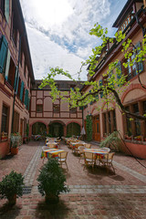Inner yard of Colorful half-timbered houses in the old town in Colmar, Haut Rhin in Alsace, France. People on the background