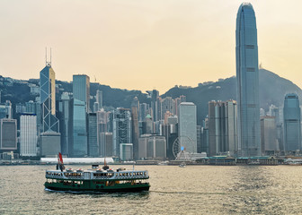 Star ferry at Victoria Harbor and Hong Kong skyline at sunset. View from Kowloon on HK Island.