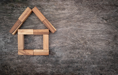 Obraz na płótnie Canvas wooden blocks arranged in a house-shaped logo on a wooden background