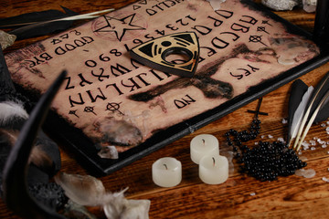 Ouija Board with candles. Seance on wooden table. The mystical atmosphere of the call of spirits....