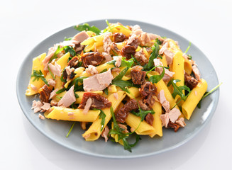Penne pasta with tuna chunks, rucola and dry tomatoes