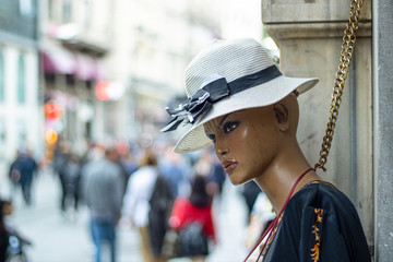 Lifeless mannequins standing in front of the store. There are clothes on the tops.