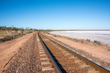 Railway track leading into the distance with salt lake next to it.