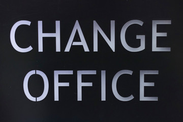 Signpost belonging to the exchange office. Close-up. White text on black signboard.