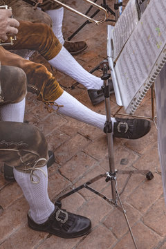 piernas de hombre con vestimenta de m&uacute;sico tradicional, y atril con partituras musicales 