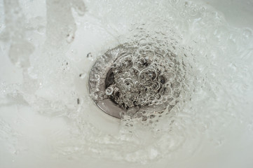 Draining transparent water into the bathroom drain.