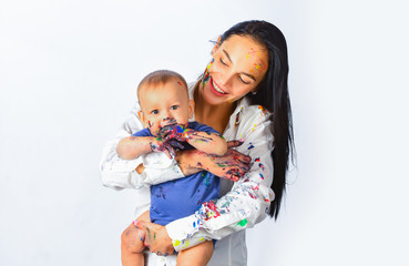 Young mother holding her newborn child. Baby soiled by paints with mother. Mom hugging and carrying...