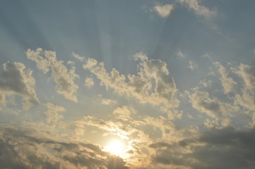 The light of the rising sun in the morning surrounded by clouds.