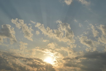 The light of the rising sun in the morning surrounded by clouds.