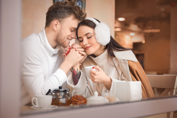 Happy young couple sitting in cafe, view through glass window