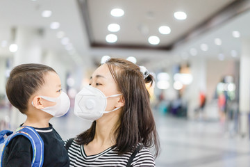 Coronavirus and Air pollution pm2.5 concept.Little chinese boy and chinese mother wearing mask for protect pm2.5 and kissing mom in Airport terminal.Wuhan coronavirus and epidemic virus symptoms.