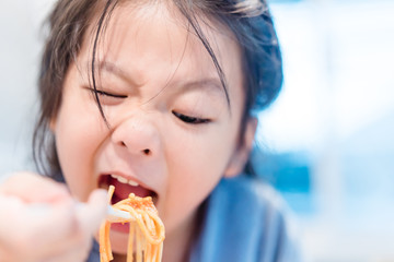 Hungry face and enjoy eating concept.Little asian girl enjoy eating with spaghetti bolognese with cheese on a plate in lunch time at restaurant.