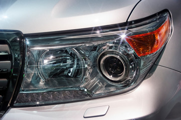 Car headlight with led and xenon lamps of modern powerful offroader vehicle with silver gray bodywork, automobile industry