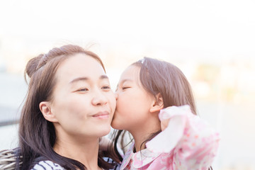 Happy loving asian family.Asian mother and child girl playing, kissing and hugging in sunset time.Laughing attractive asian mother and her cute little asian daughter at home.