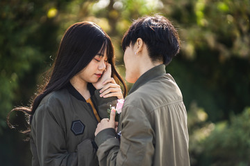 LGBT lesbian couple holding hands each other while his hands gently touched her cheek.