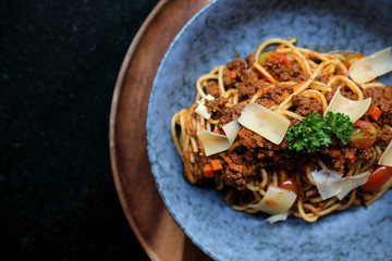 spaghetti Bolognese with minced beef and tomato sauce garnished with parmesan cheese and basil , Italian food