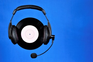 Vinyl record retro sound carrier and headphones for listening to music and speech. The record is played on a club player or gramophone.