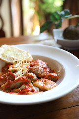 Homemade spinach Ravioli pasta with sausage in tomato sauce on wood background , italian traditional food