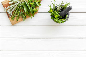 Make seasoning and condiments. Herbs in mortar on white wooden background top-down copy space