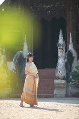 Fototapeta na wymiar Portrait of Thai female with traditional Thai dress walking with temple background