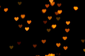 Black background with bright warm heart shaped bokeh lights. Holiday, Valentines Day background. Ideal to layer with any design. Horizontal