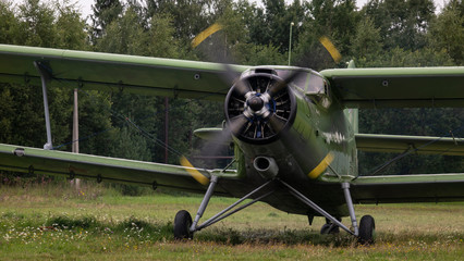 Agricultural airplane stands in a field in the green grass.