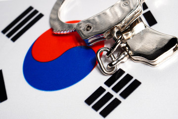 Handcuff on the flag of Republic of Korea. Close-up, copy space