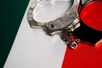 Handcuff on the flag of Italy. Close-up, copy space