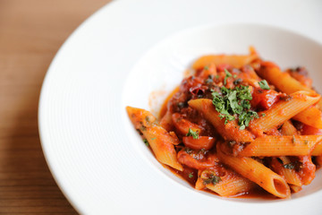 Penne arrabiata pasta tomato sauce with spices italian food on wood background
