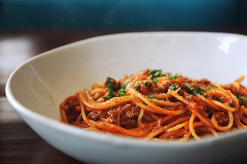 spaghetti Bolognese with minced beef and tomato sauce garnished with parmesan cheese and basil , Italian food