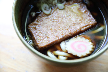 kitsune udon noodles with fish ball and tofu on wood background japanese food