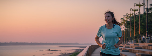 Woman running on street with a view of river in the morning.