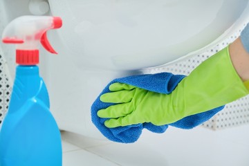 Close-up of hand in gloves with rag and detergent washing hanging toilet