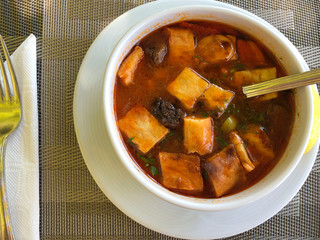 Food. White plate with soup on the table in an outdoor cafe. Tomato soup with crackers in a white plate. Top view, horizontal, close-up. The concept of a healthy diet.