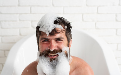 Taking bath with soap suds. Brutal muscular man in bathroom. Man style and fashion concept. Soap...