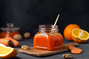 Can with vegetable carrot jam and spoon on a dark background