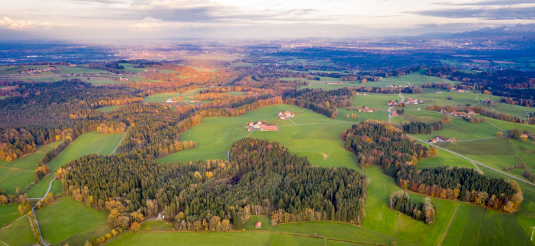 Aerial view Autumn landscape in Bavaria near Miesbach. Road going into the distance and the peaks of the Alps on the horizon. Clouds sky, Yellow trees and green field