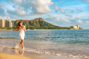 Hawaii vacation woman relaxing on Waikiki beach running carefree enjoying holidays in Honolulu City...