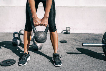 Fototapeta na wymiar Kettlebell weightlifting athlete woman lifting weight at outdoor fitness gym. Lower body legs and feet closeup of strength training legs, glutes and back lifting free weights.