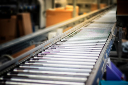 Fully automated logistics warehouse with a conveyor belt. Background is blurred. It is a modern storage