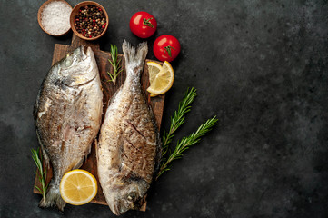 grilled dorado fish on a cutting board with spices and lemon on a stone background  with copy space for your text