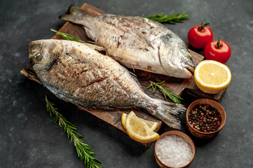 grilled dorado fish on a cutting board with spices and lemon on a stone background